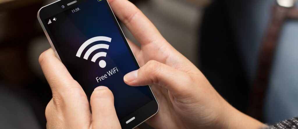 Person holding smartphone with free WiFi symbol on screen, illustrating internet connectivity access.