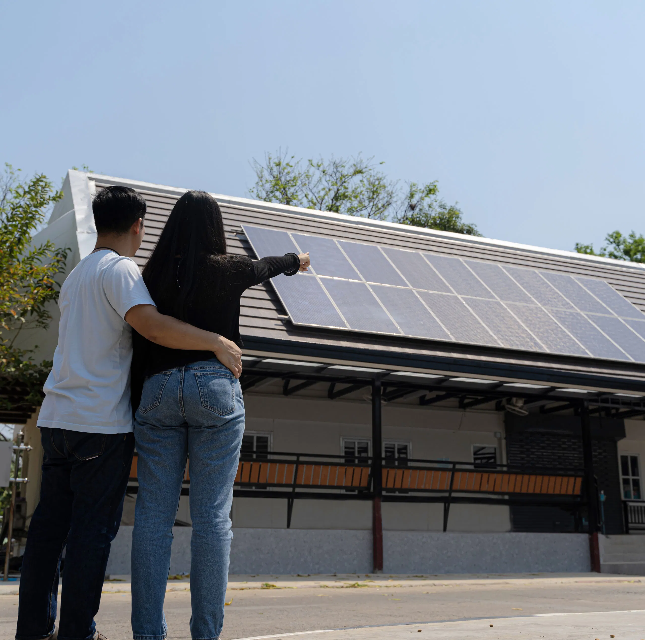 Couple admiring solar panels on a home's roof, embracing sustainable energy and eco-friendly living.