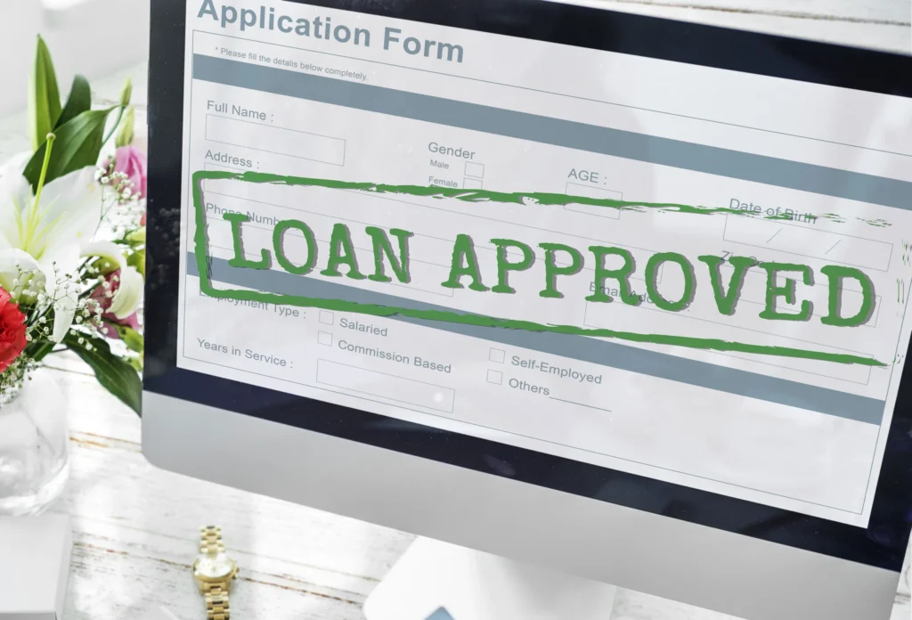 Computer screen showing a loan application form with LOAN APPROVED stamped in green.