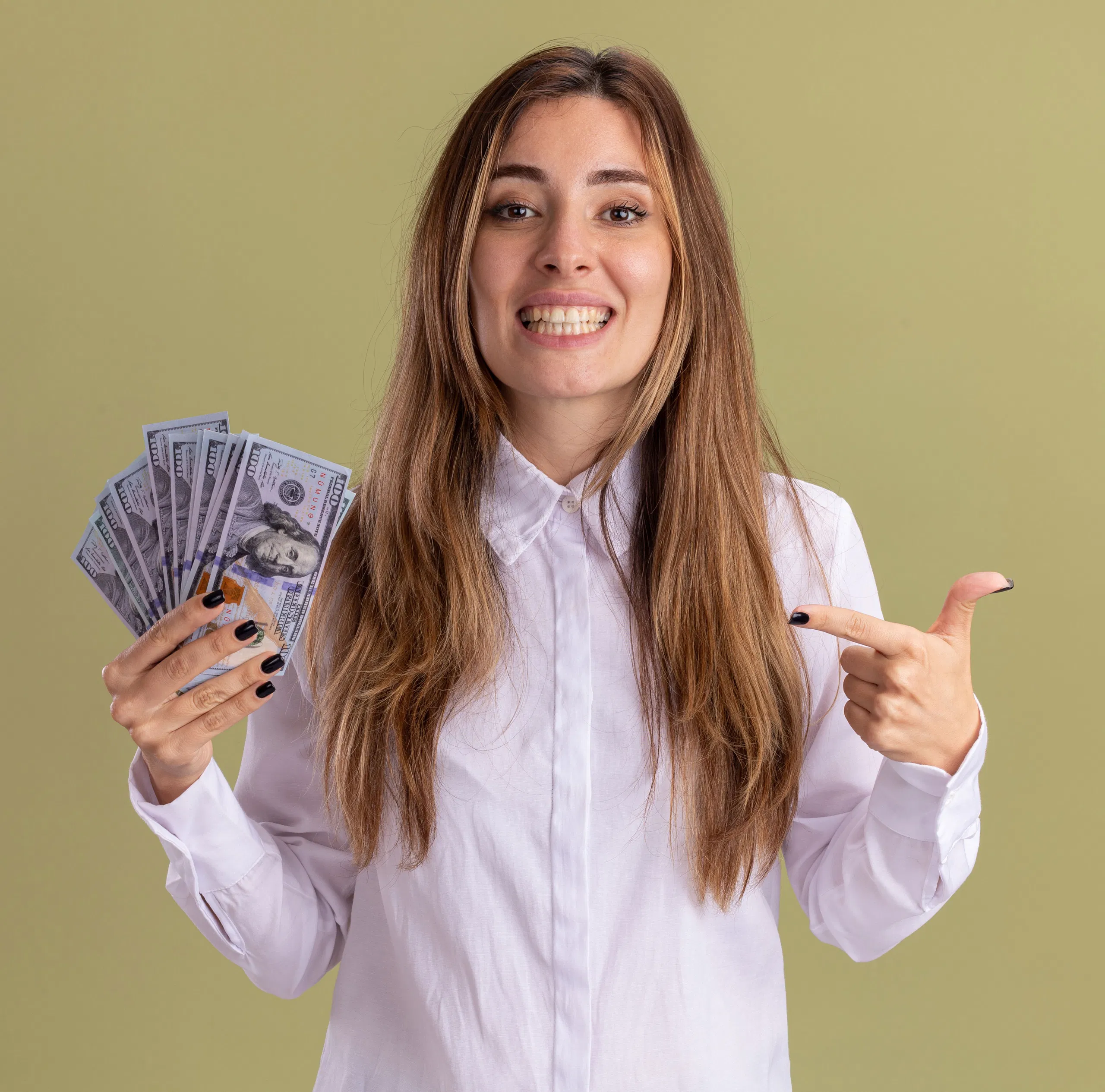 Woman in white shirt smiling and holding fanned out US dollar bills, pointing with finger.