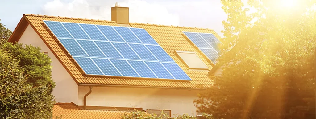 Sunny house with solar panels on the roof, surrounded by trees, showcasing renewable energy and sustainability.