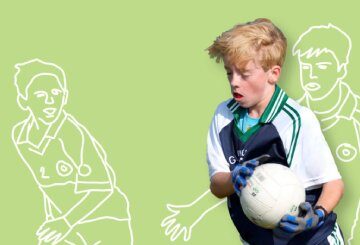 Young boy in sports uniform playing Gaelic football with illustrated players on a green background.