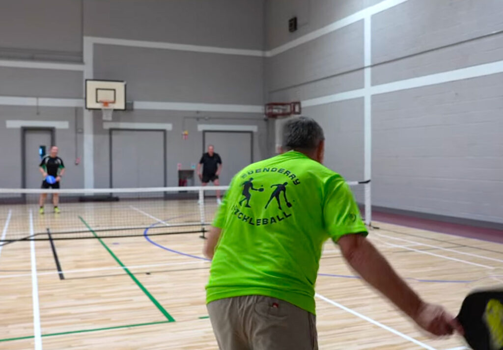 Players engage in a pickleball match indoors, highlighting dynamic gameplay and sports enthusiasm.