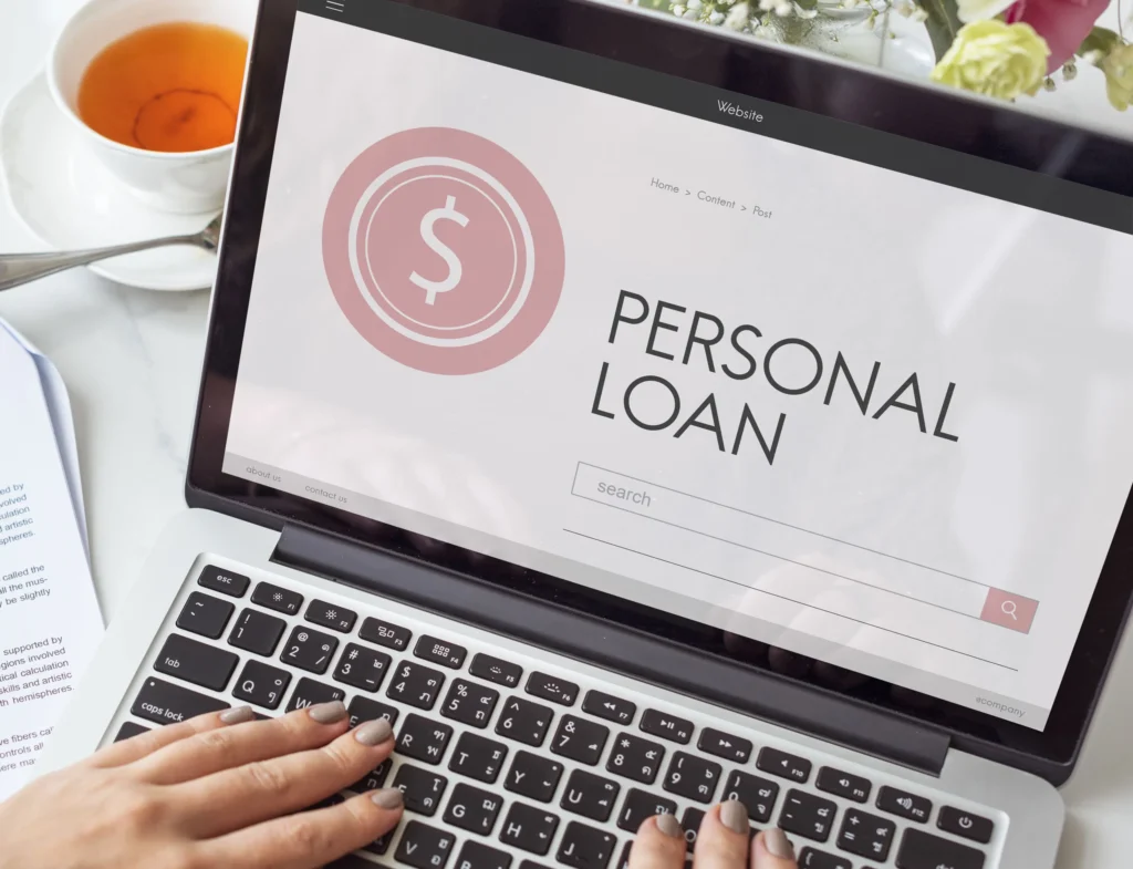 Person researching personal loan options on laptop with coffee nearby.