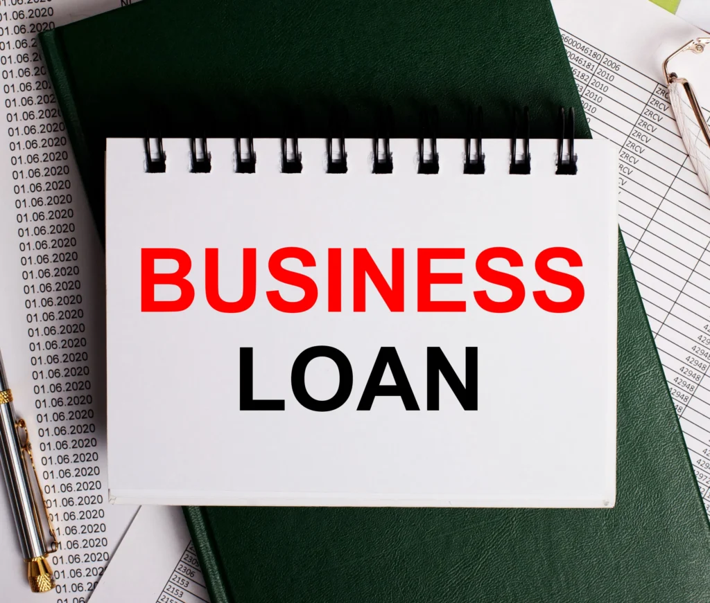 Notebook with Business Loan text, placed on financial documents and a pen for business financing concept.