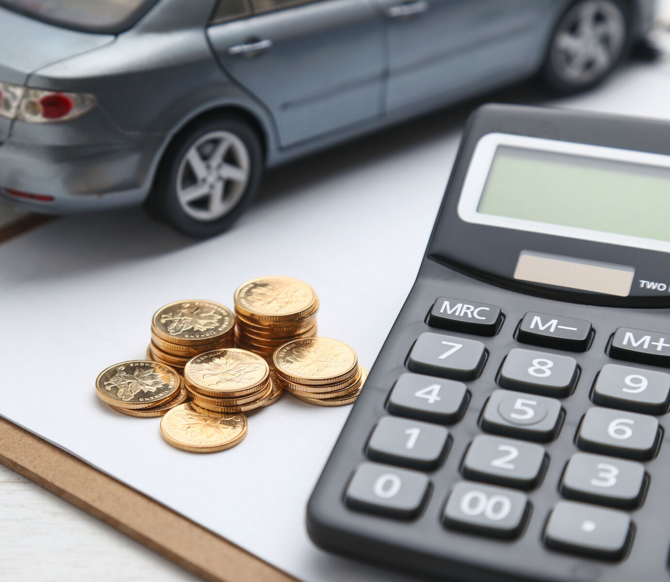 Calculator, coins, and car model symbolize auto finance and budgeting.