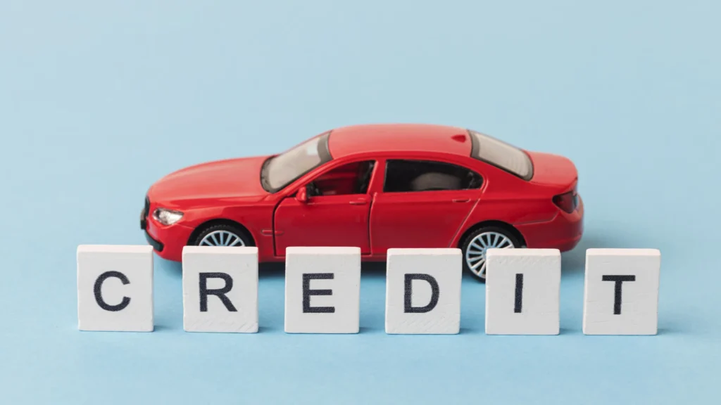 Red toy car with the word CREDIT spelled in blocks, representing car financing or credit options.