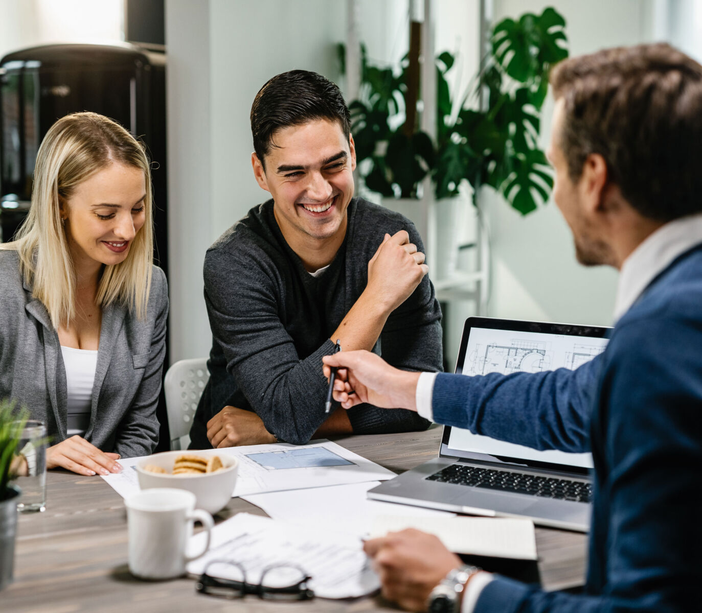 Young couple discussing building plans with an architect in a modern office setting.