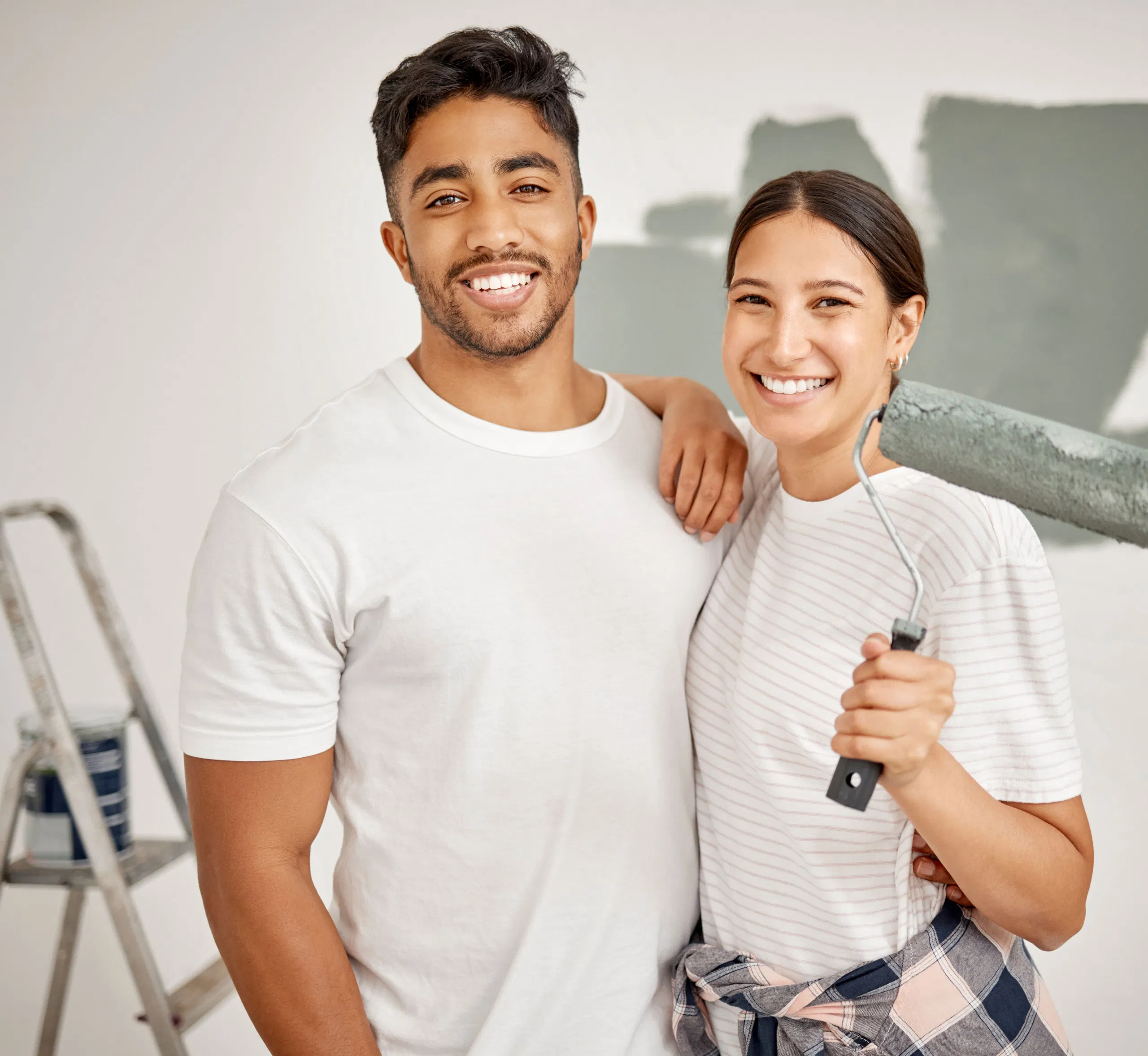 Couple smiling while painting a wall with roller, home renovation concept.