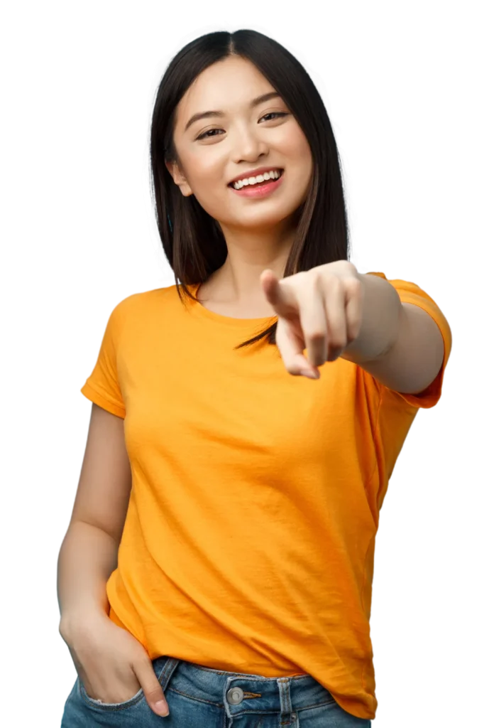 Smiling person pointing forward, wearing orange shirt and jeans. Confident pose with hand in pocket.