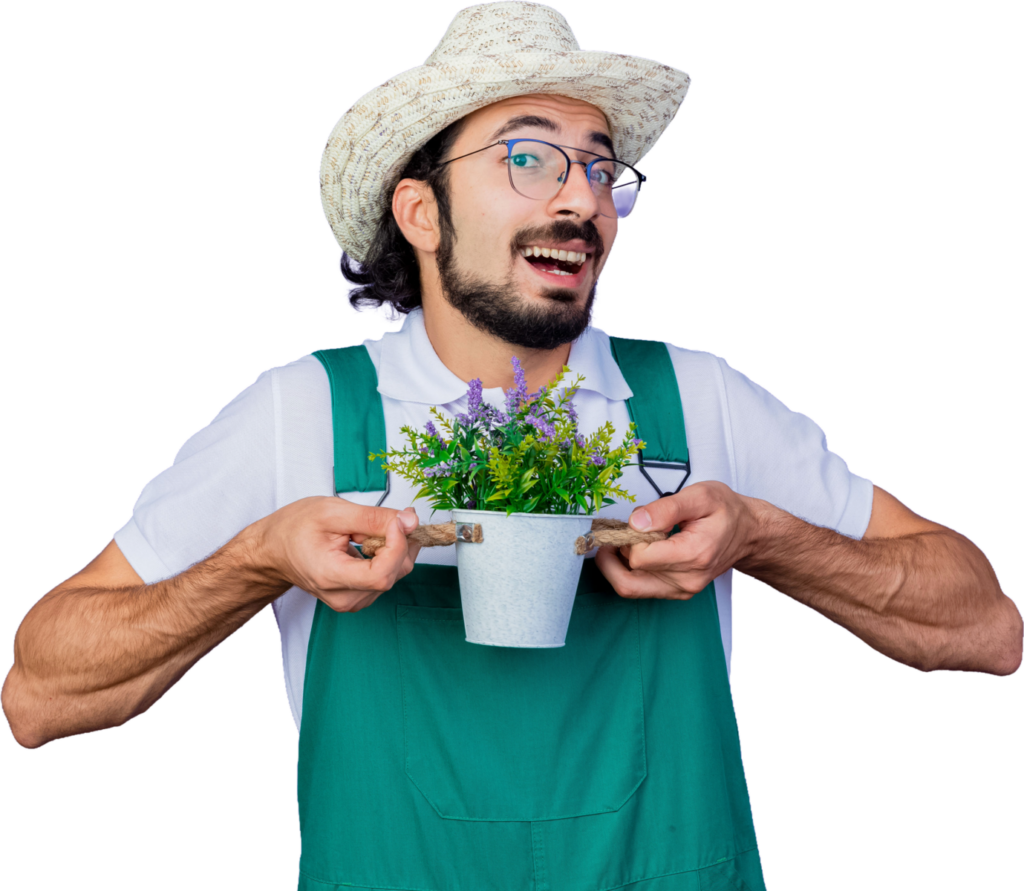 Smiling gardener in green overalls holding a small potted plant with lavender flowers, wearing a straw hat.