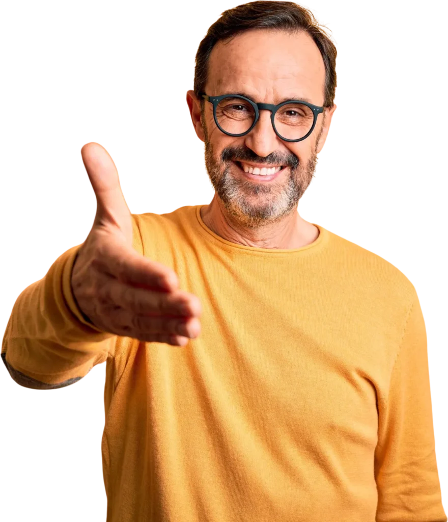 Man in glasses extending hand for a handshake, wearing a yellow sweater, smiling with a friendly expression.
