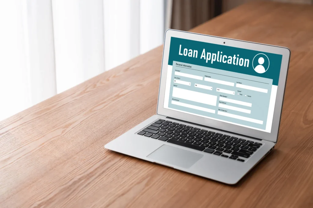 Open laptop displaying an online loan application form on a wooden desk.