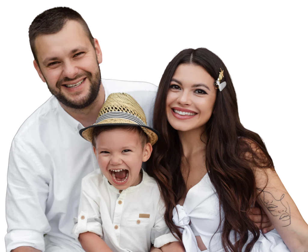 Happy family portrait with parents and child smiling, wearing casual white outfits and a straw hat.