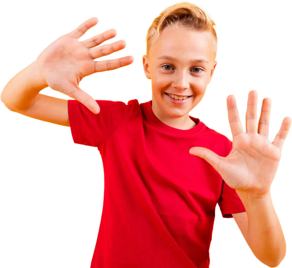 Smiling child in a red shirt holding up ten fingers against a white background, expressing excitement and joy.