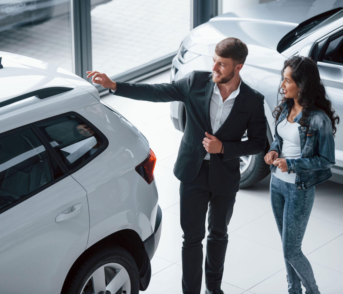 Car salesperson showing a vehicle to a customer in a dealership.